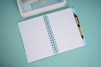 Spiral notebook with pen, open to lined pages