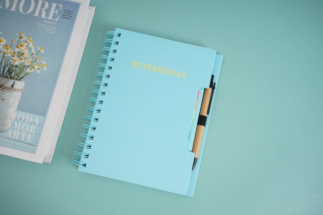 Spiral notebook with pen and sticky notes, 'NOTES&IDEAS' text visible on cover