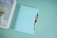 Spiral notebook with pen and sticky notes, 'NOTES&IDEAS' text visible on cover
