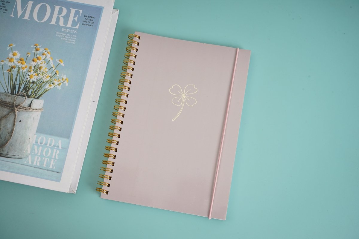 Pink elegant notebook with gold spiral binding and white bow on front cover
