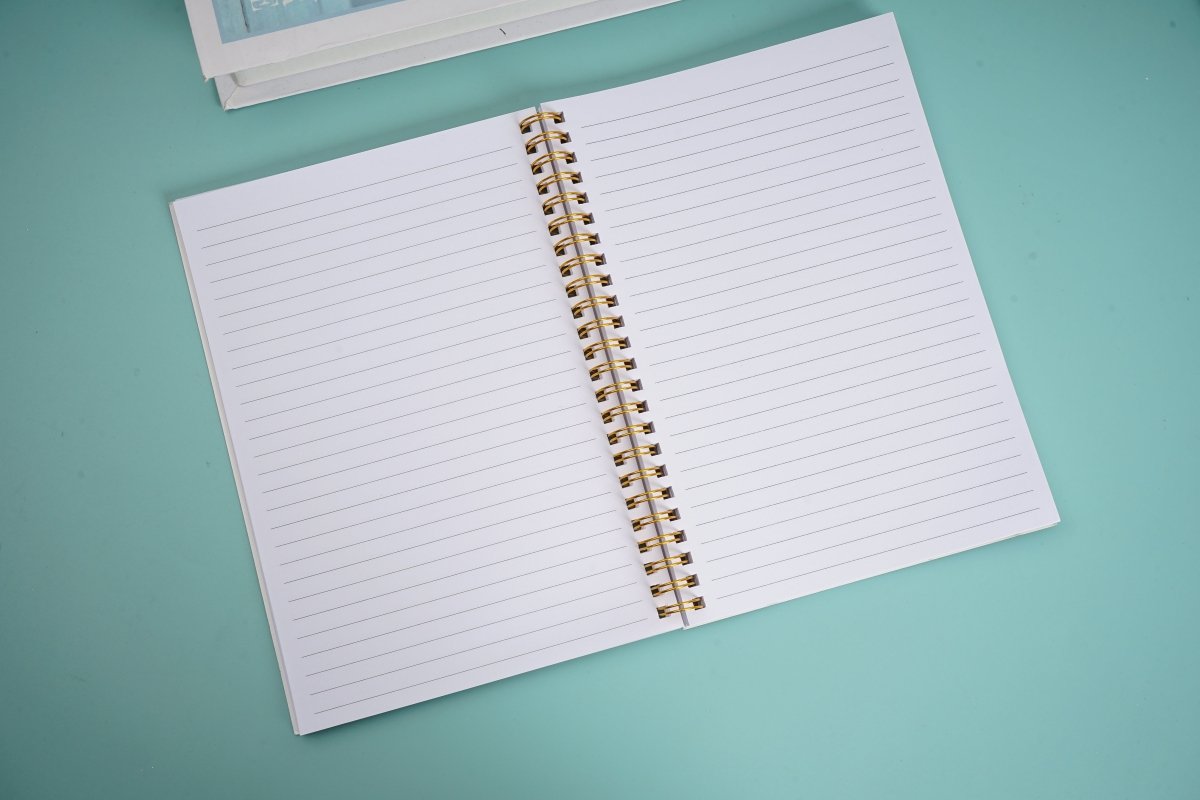 Open notebook with white lined pages and gold spiral rings, viewed from above