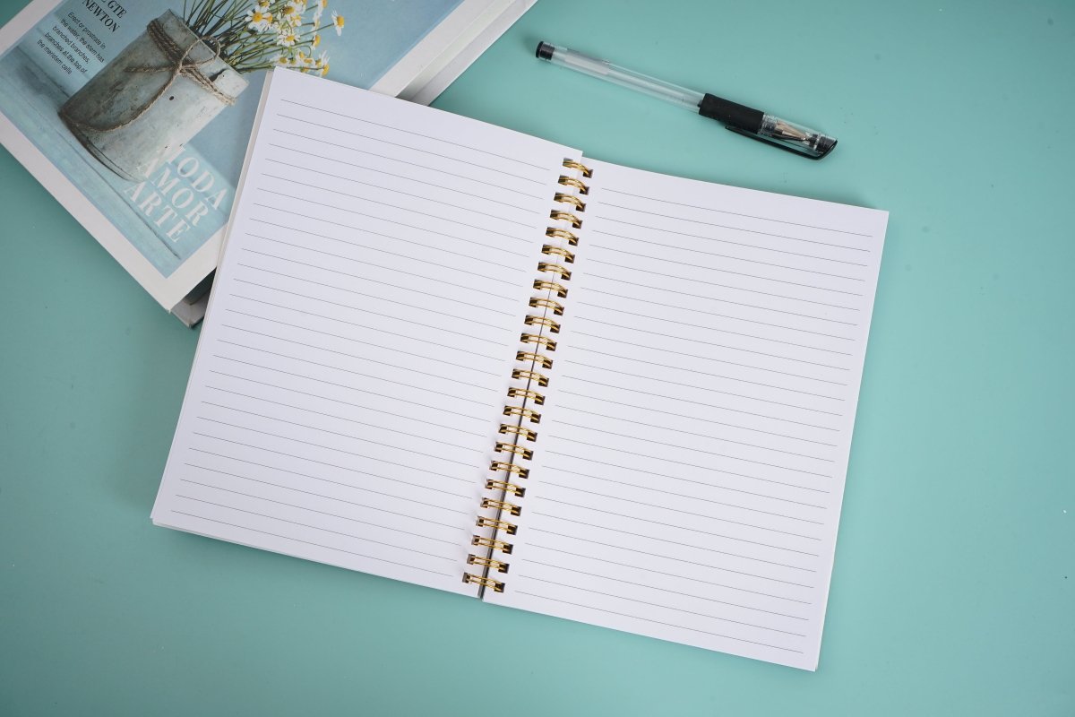 Open notebook with white lined pages and gold coil spiral binding
