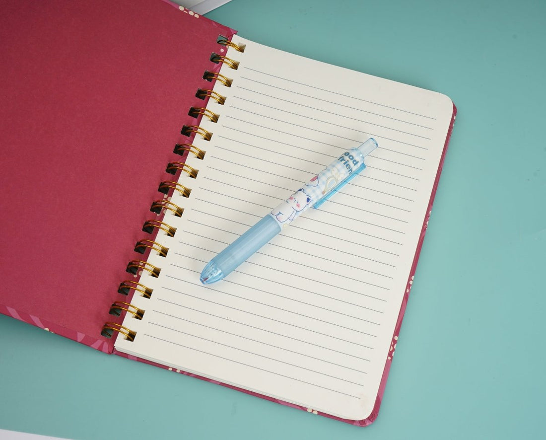Open pink floral coil notebook with lined pages and gold spiral rings