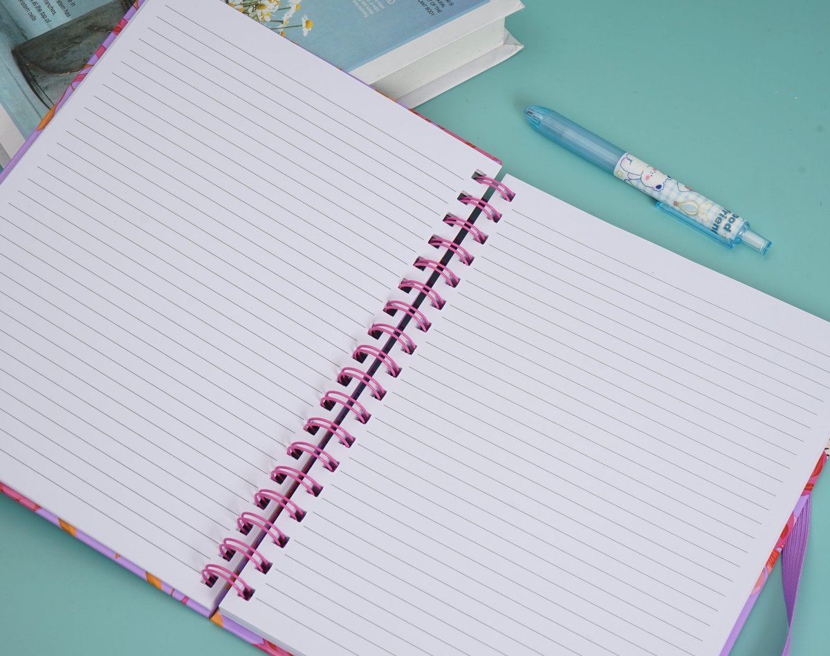 Open lined notebook pages with pink spiral coil; pens and notes beside it.