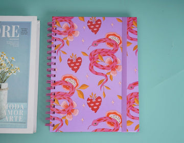Purple children's notebook with pink snake and hearts pattern, spiral coil binding.