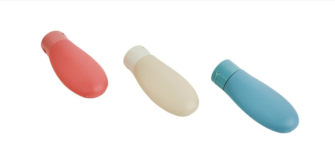 Set of 3 travel bottles in coral, cream, and teal with rounded caps.