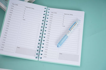 A5 daily planner notebook with turquoise coil binding and printed weekly schedule pages