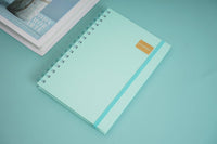 A5 daily planner notebook with light turquoise cover, gold label, and spiral binding
