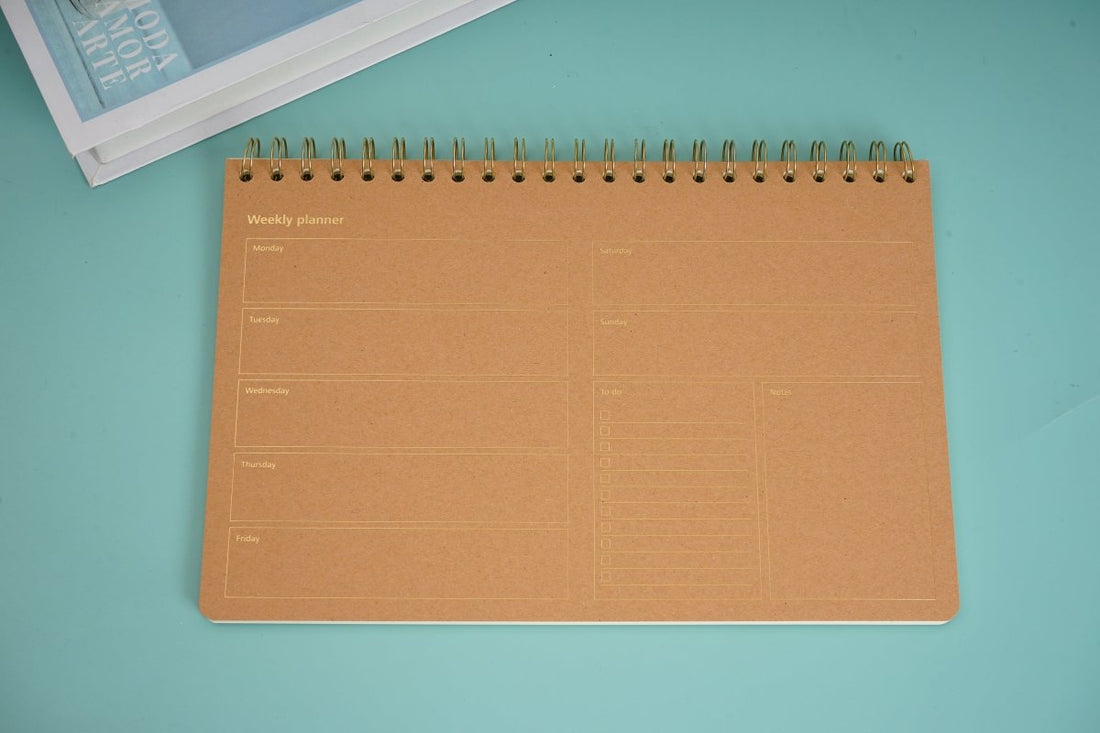 Weekly planner notebook with wood-grain cover and black spiral coil binding