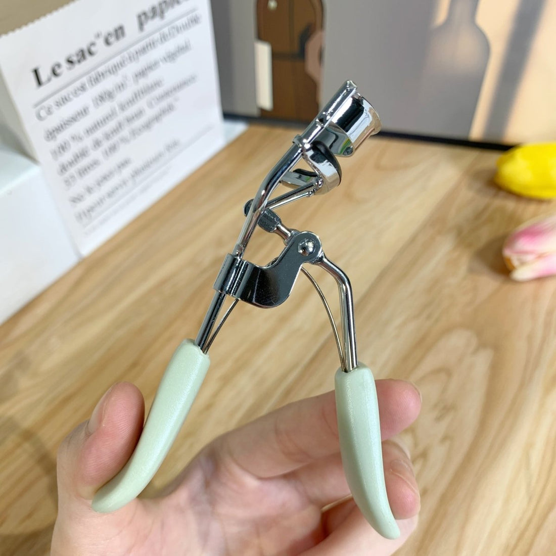 Eyelash curler with chrome frame and pale mint handles, handheld clamp