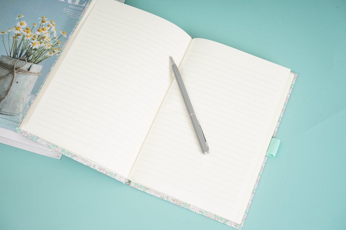 Floral notebook open with lined pages and pen in side loop