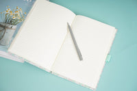 Floral notebook open with lined pages and pen in side loop