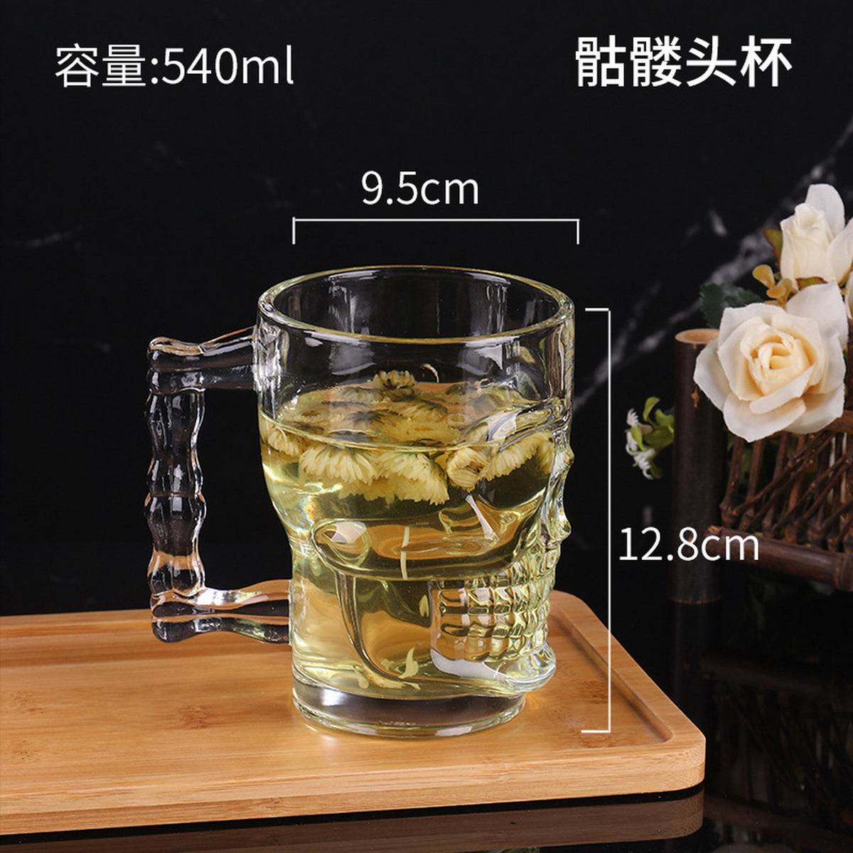 Clear glass skull mug with right handle, filled with tea and floating flowers