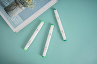 Green highlighter markers, two pens shown with green caps and white bodies