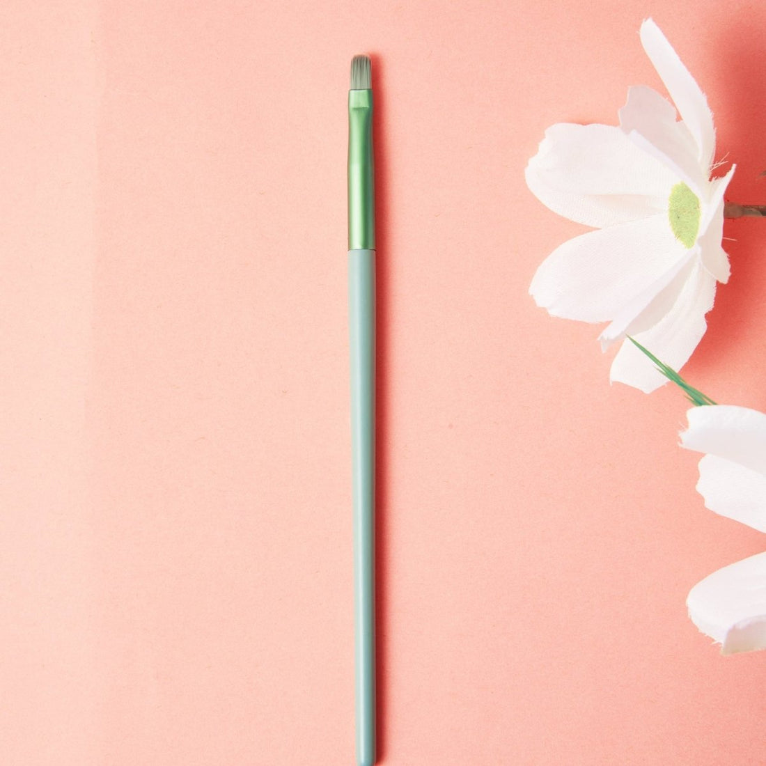 Fine oil painting brush with long teal handle and green cap, pointed tip