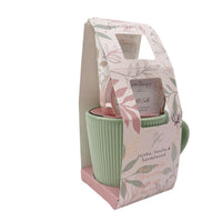 Gift set bag holding a green striped mug with bath salt and lotion tube