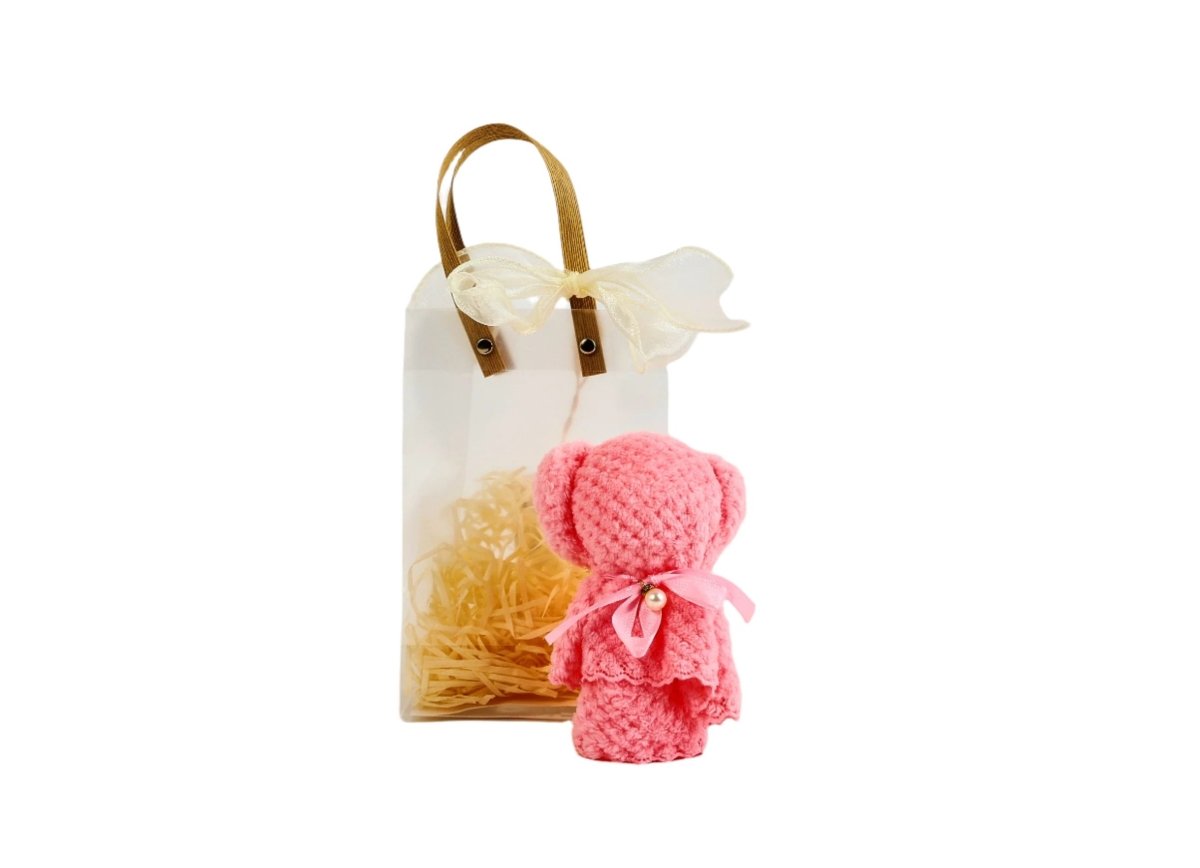 Pink towel bear in small gift bag with bow handle and straw filler