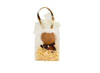 Brown towel bear in white gift bag with straw filler and black bow