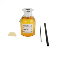 Reed diffuser bottle with yellow liquid, silver top, two black reeds, and refill pads