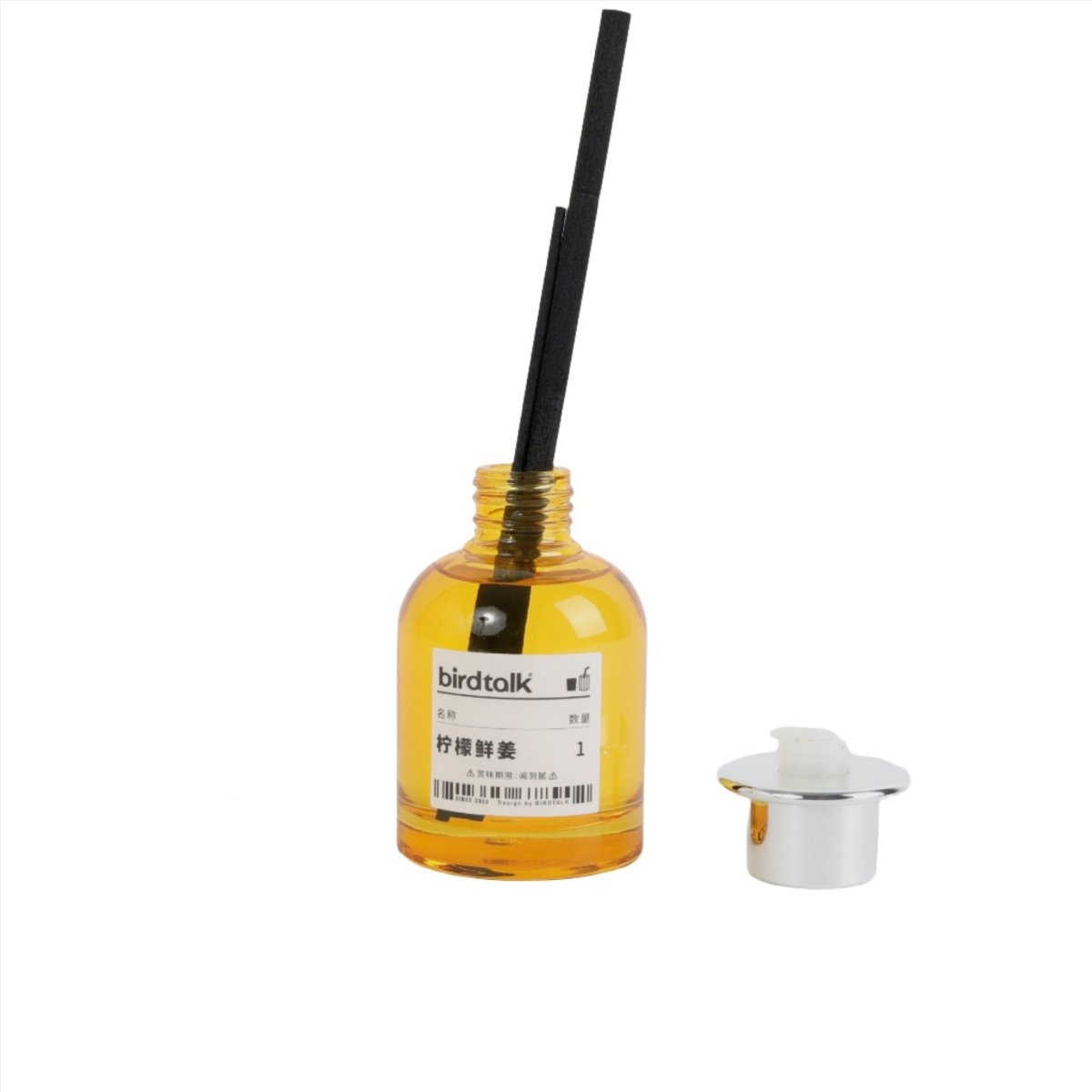 Reed diffuser bottle with yellow liquid, black reeds, and gold cap