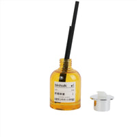 Reed diffuser bottle with yellow liquid, black reeds, and gold cap