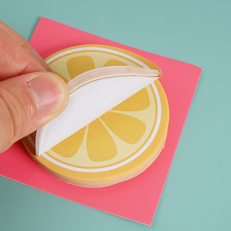 Lemon slice sticky notes: hand lifting a white sheet from the lemon slice pad