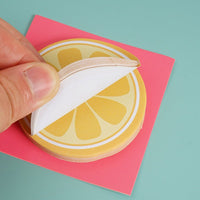 Lemon slice sticky notes: hand lifting a white sheet from the lemon slice pad
