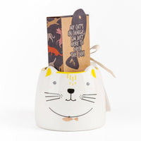 White ceramic cat-face mug with yellow handle, kraft gift set box behind