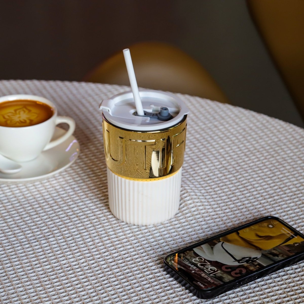 Ceramic coffee cup with lid and white straw, gold band and ribbed white base