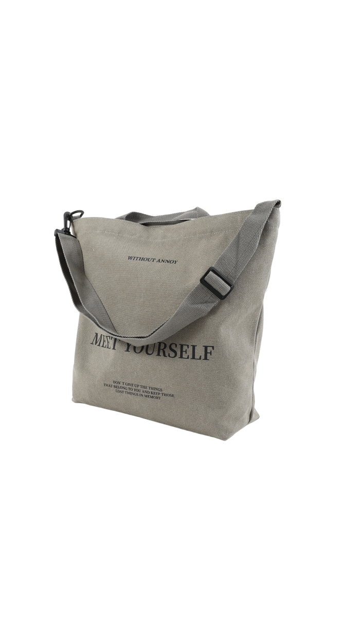 Gray canvas tote bag with printed 'MEET YOURSELF' and shoulder strap buckle.