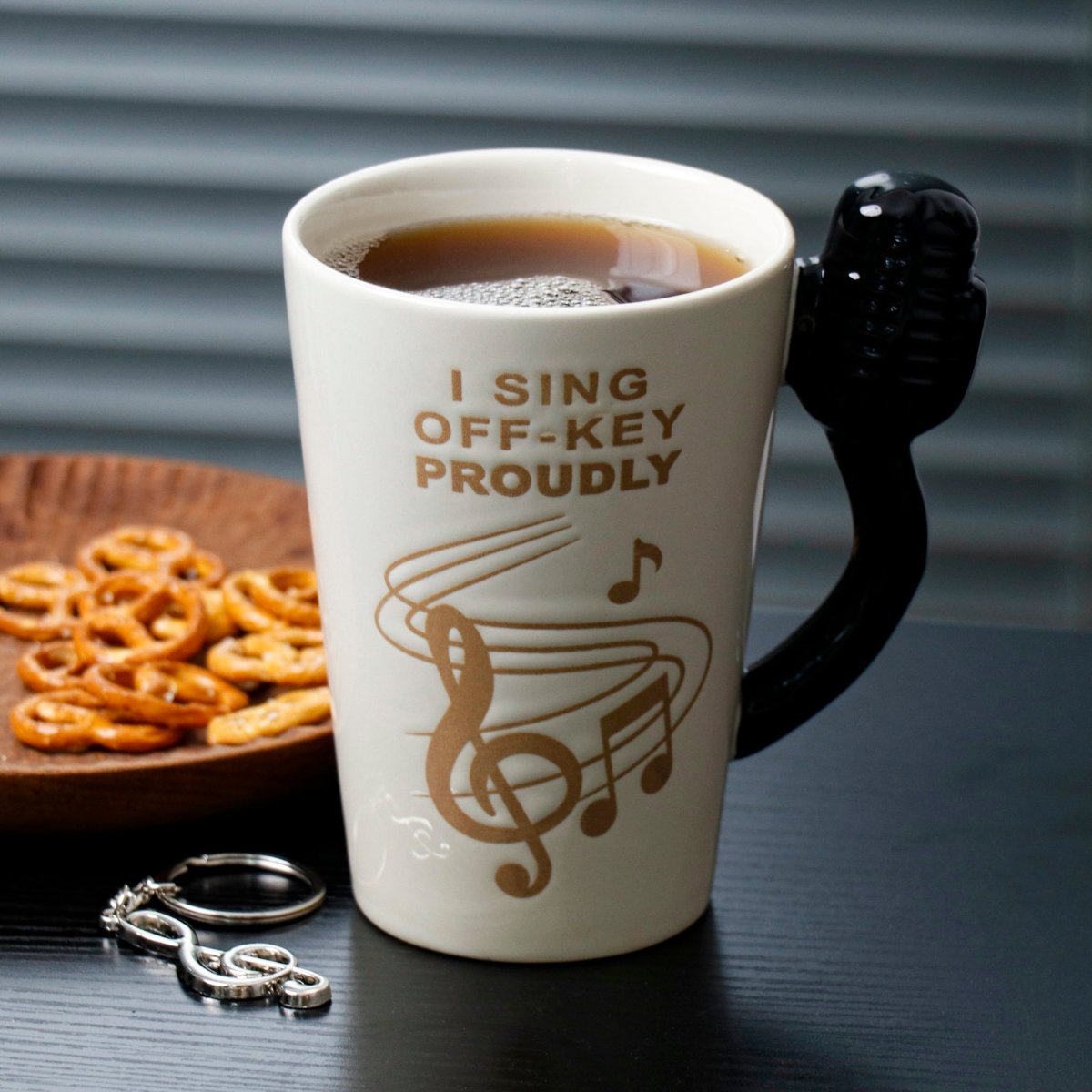 Beige ceramic karaoke cup with black microphone handle, filled with dark coffee
