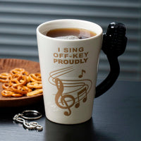 Beige ceramic karaoke cup with black microphone handle, filled with dark coffee
