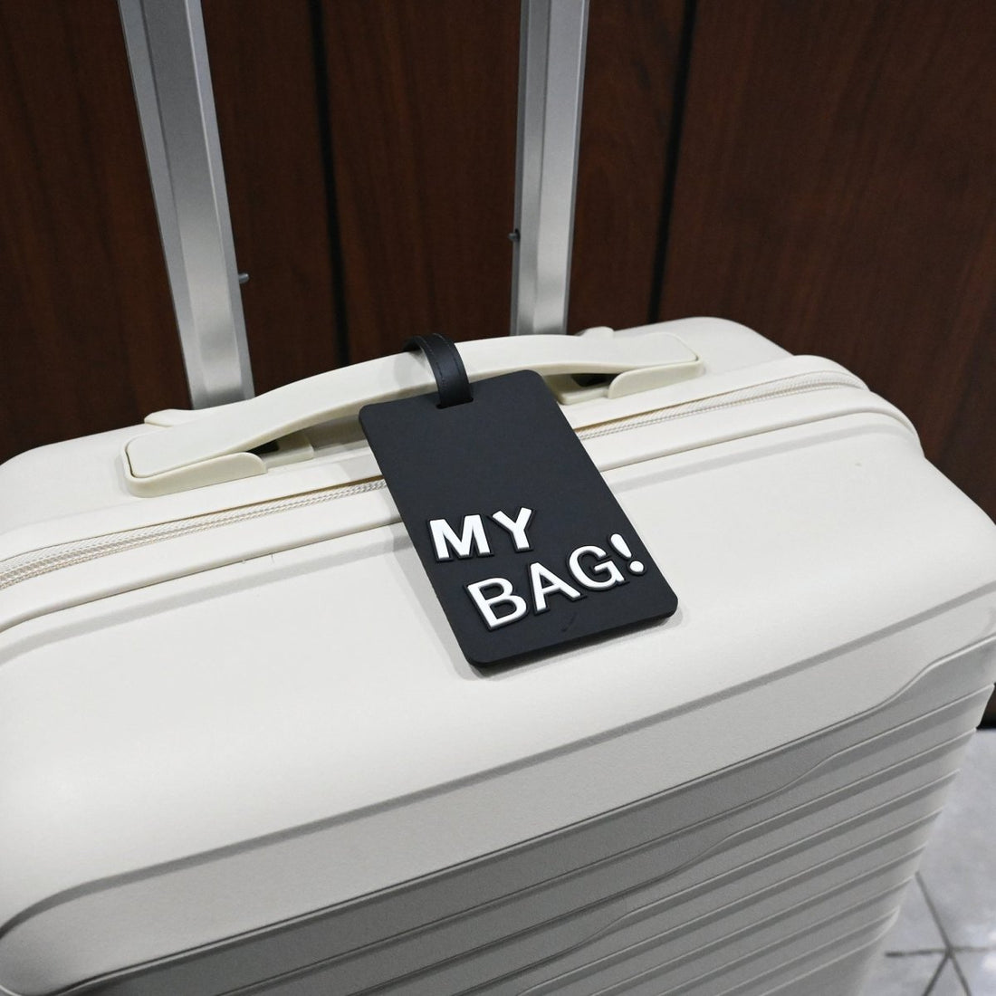 Luggage ID tag on a white suitcase, red “MY BAG!” card and black strap.