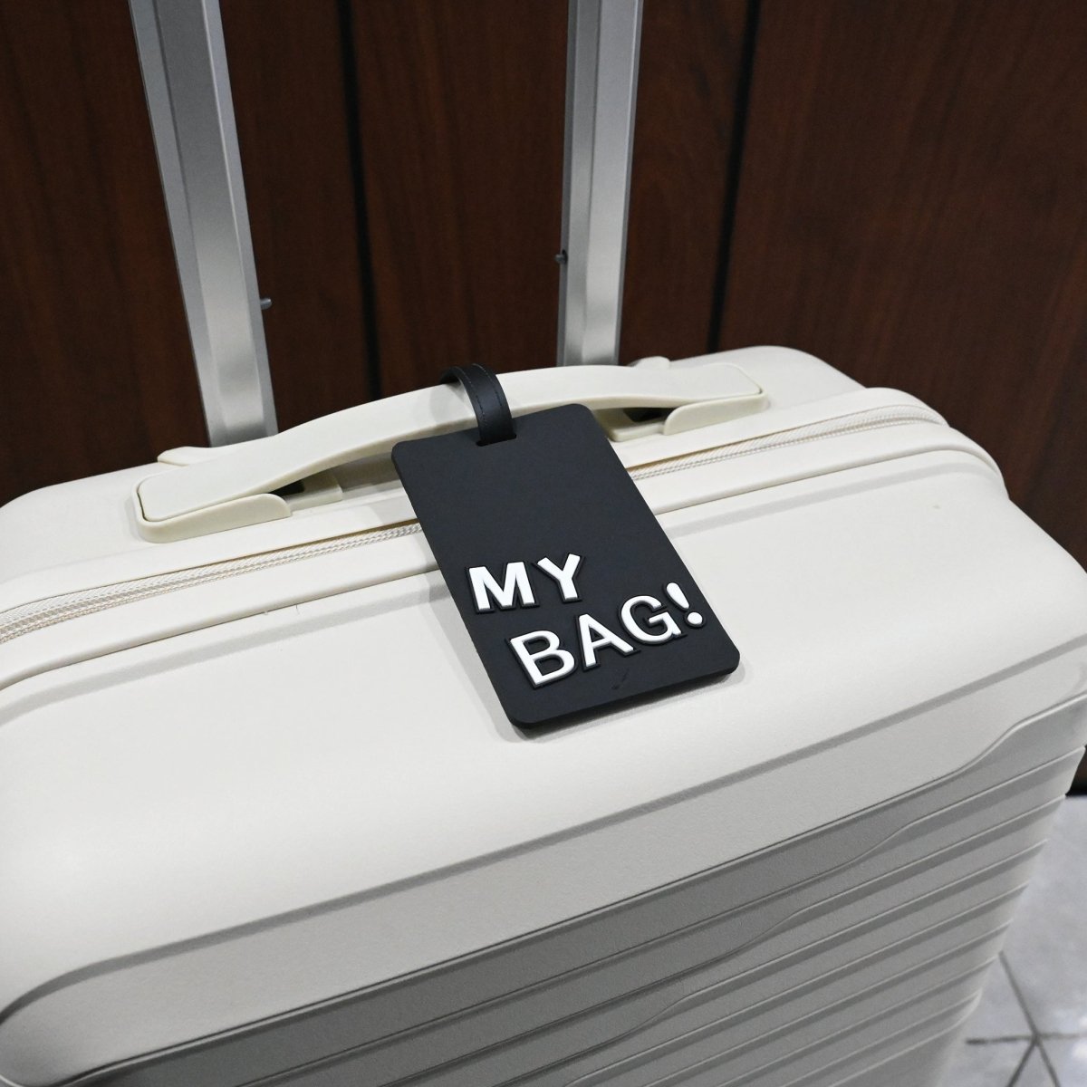 Luggage ID tag on a white suitcase, red “MY BAG!” card and black strap.