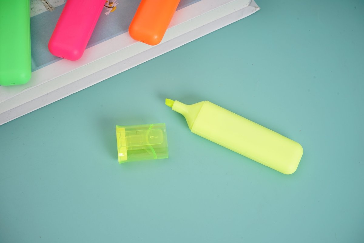 Neon yellow highlighter with chisel tip, plus small yellow marker cap.