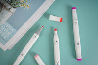 Three pink highlighters on side view, white barrels with red caps
