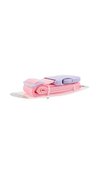 Pink luggage strap with folded webbing and gray buckle, shown laid flat.