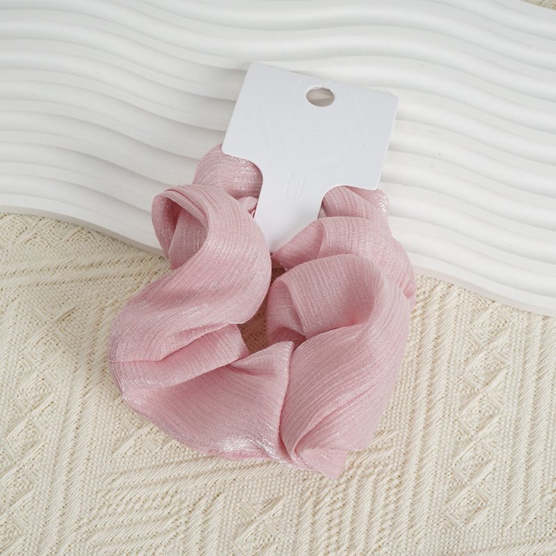 Pink woven hair scrunchie with ruffled loops and white hanging tag