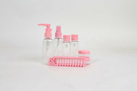 Pink travel toiletry set with pump bottle, mini bottles, jar, and comb