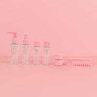 Pink travel toiletry set with pump bottles, jars, and comb accessory