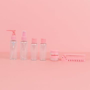 Pink travel toiletry set with pump bottles, jars, and comb accessory