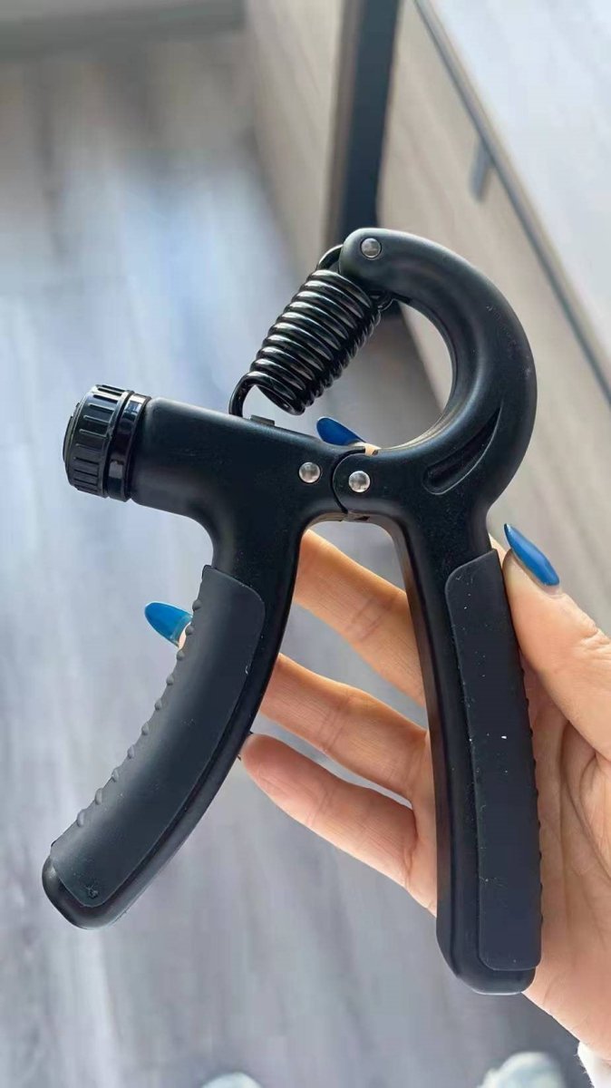 Black grip strengthener with blue handles and coil spring, held in hand