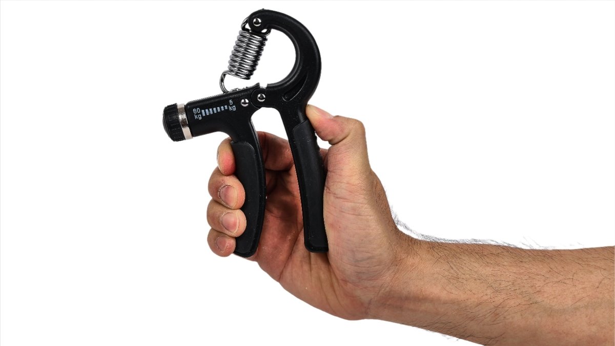 Hand holding black grip strengthener with coiled spring and finger lever