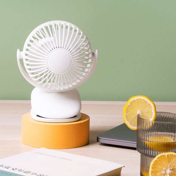 Portable mini clip fan with white circular grille on tabletop stand, adjustable head