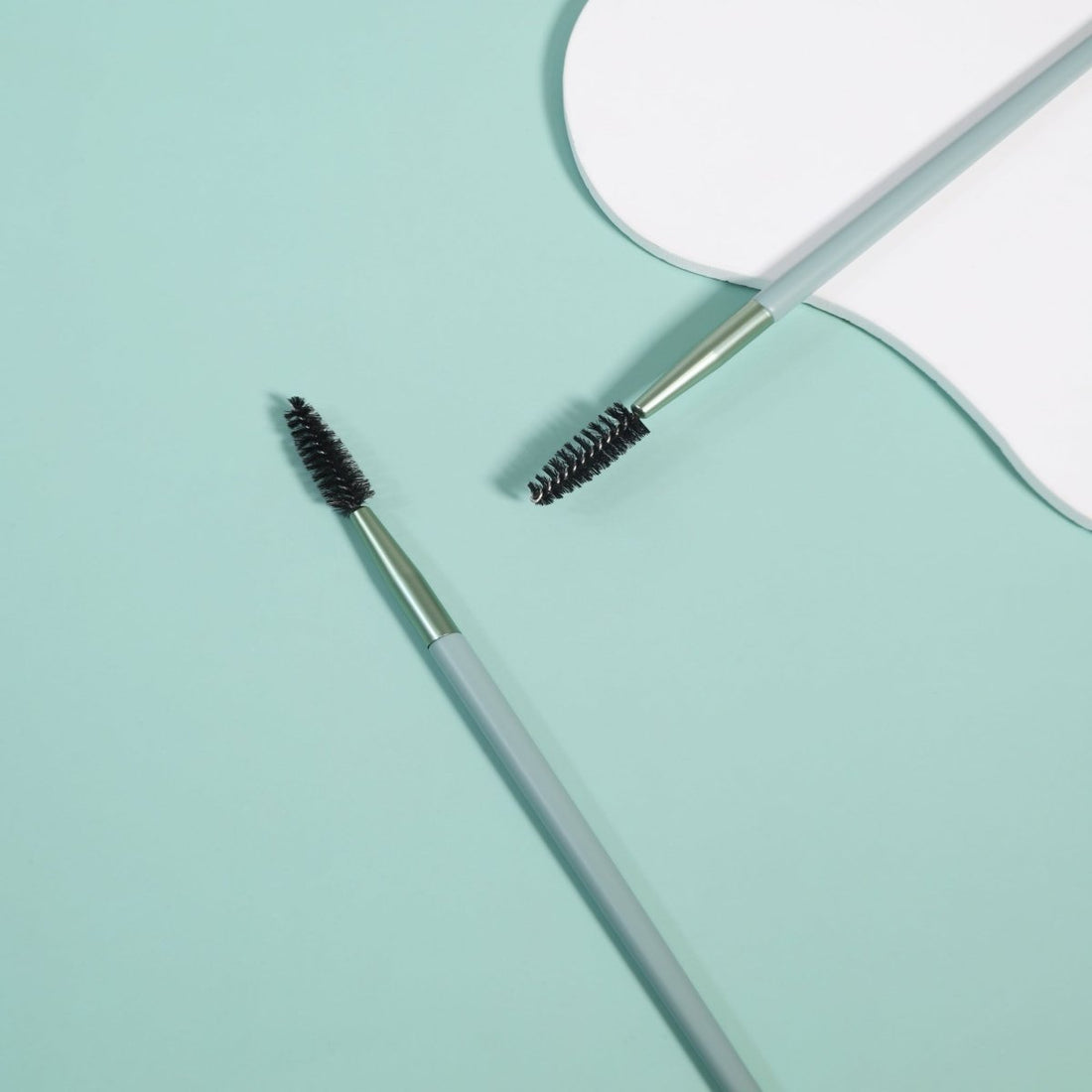 Eyebrow and lash brush with dark bristles on light gray handle
