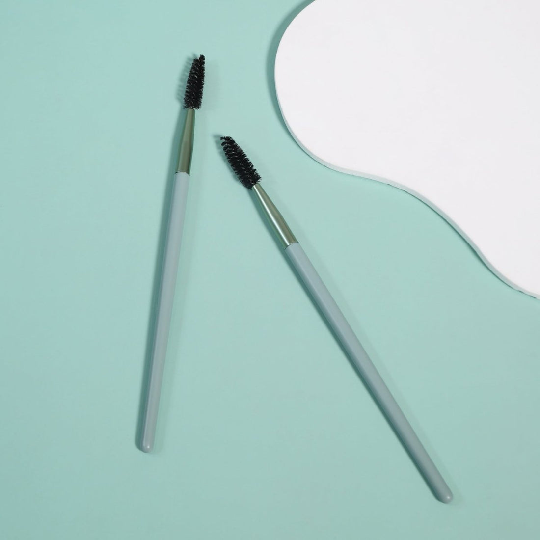Eyebrow and lash brush pair with dark bristles and silver handles