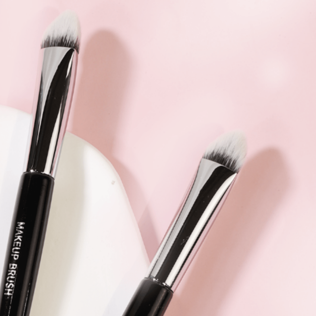 Makeup brush with black handle and angled white bristles