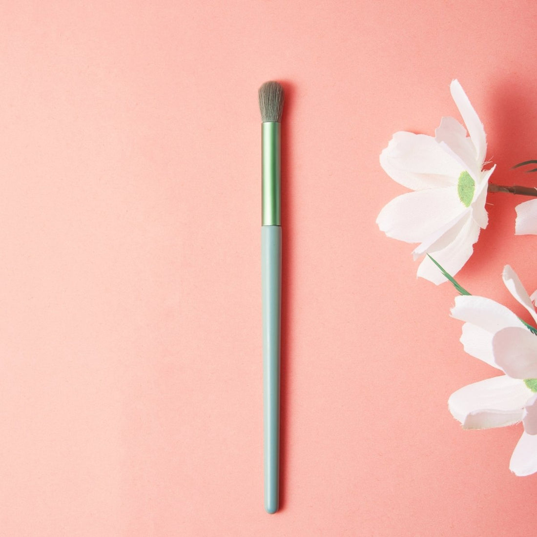 Soft makeup brush with green handle and dense gray bristles