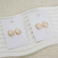 Glossy square stud earrings, cream tone, on display cards
