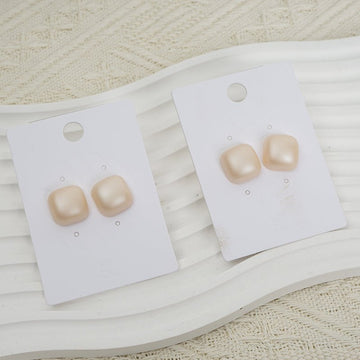 Glossy square stud earrings, cream tone, on display cards